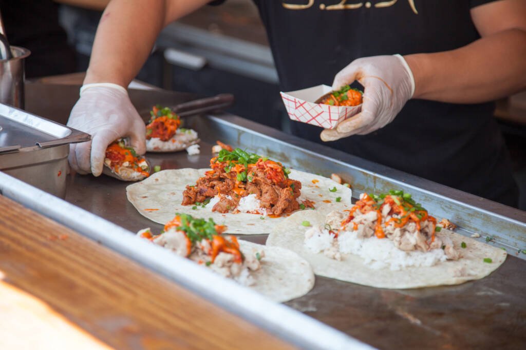 Tacos being cooked on a flat top on a food truck